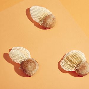 3 pieces of bread rolls with honeycomb attached on a peach background
